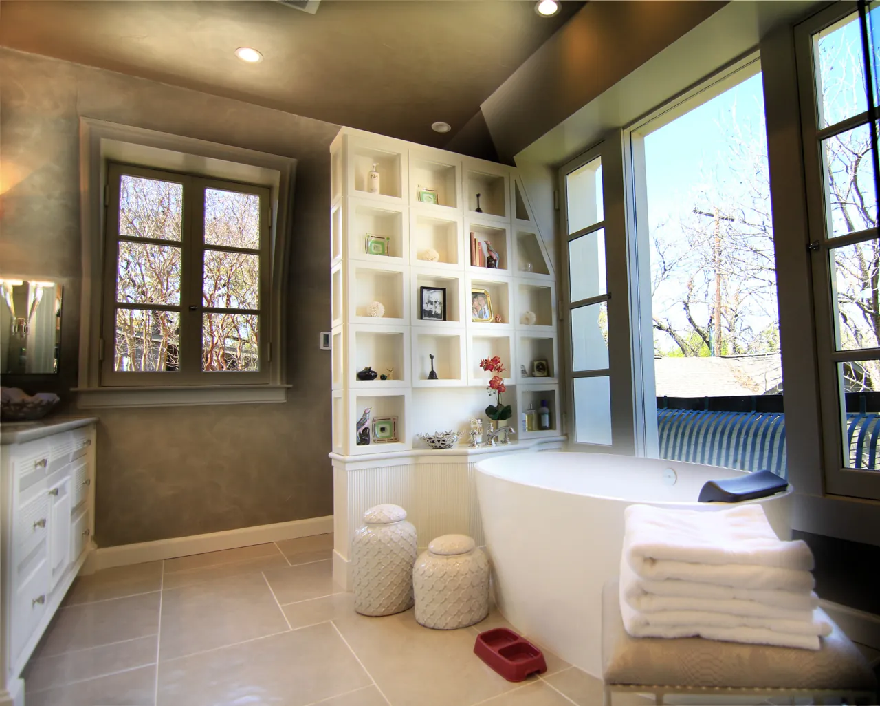White painted open shelving wall and cabinetry beside a freestanding tub