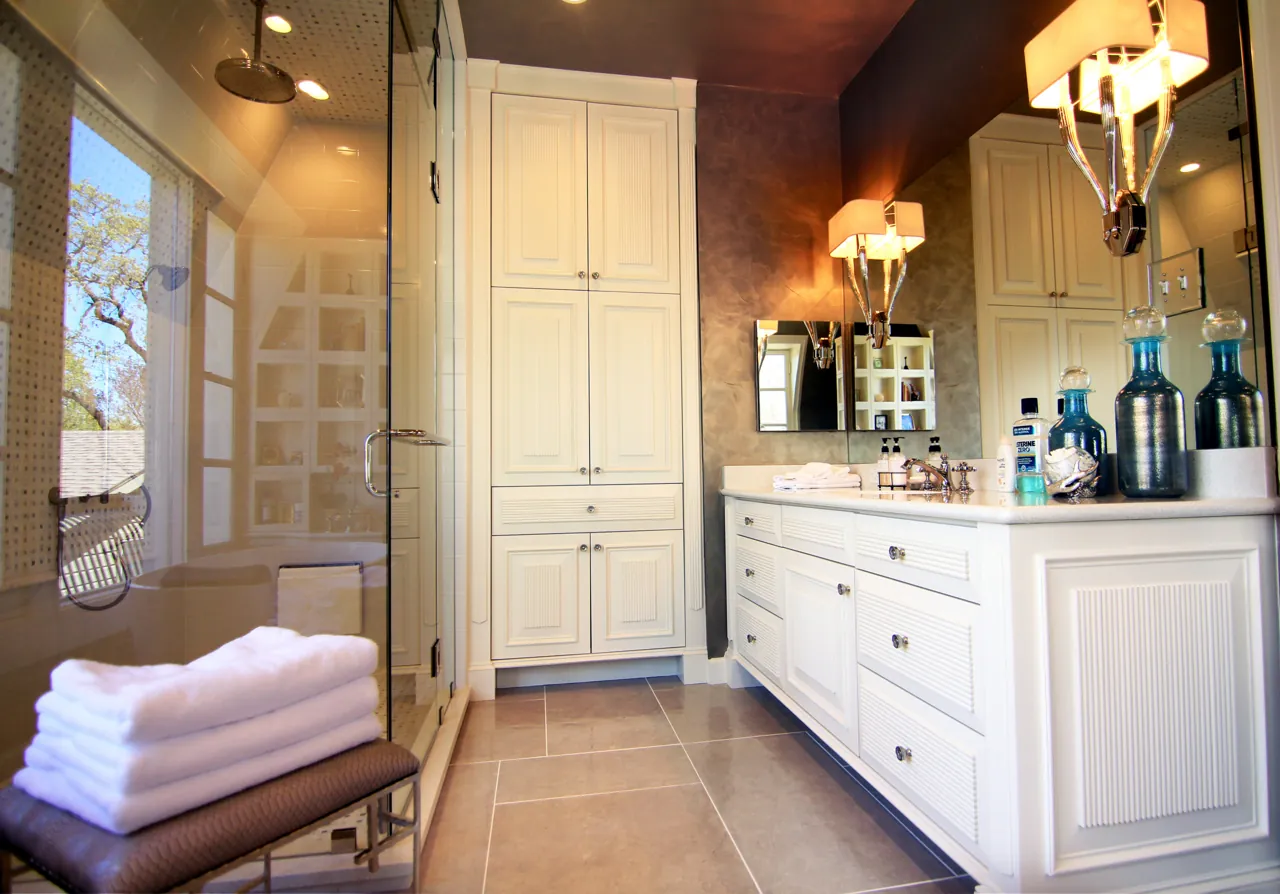 White painted bath vanity with beadboard ends beside full-height linen cabinets