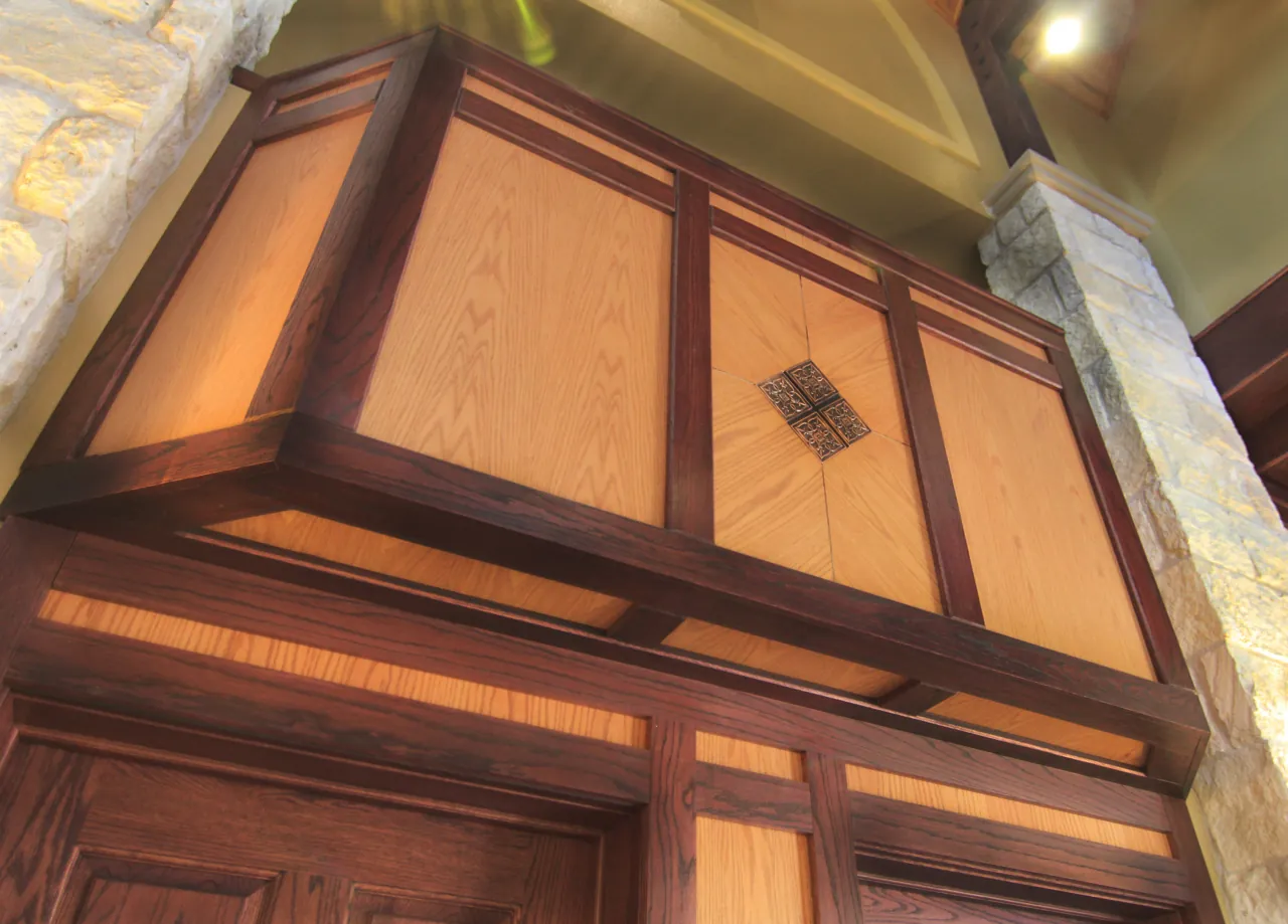Panelled wood balcony front with lit panels set between limestone piers