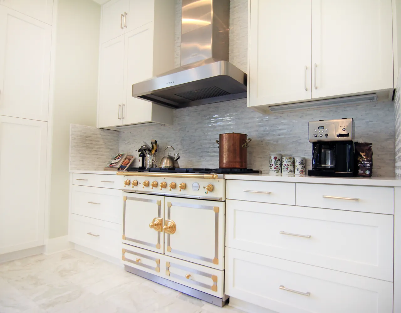 White shaker kitchen built around a white and brass French range under a stainless hood