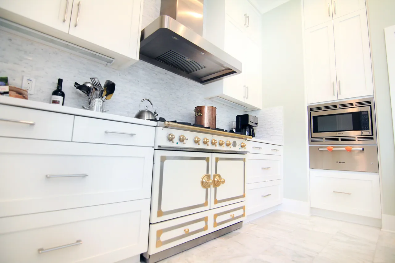 White shaker kitchen with a French range, glass tile backsplash and built-in microwave tower