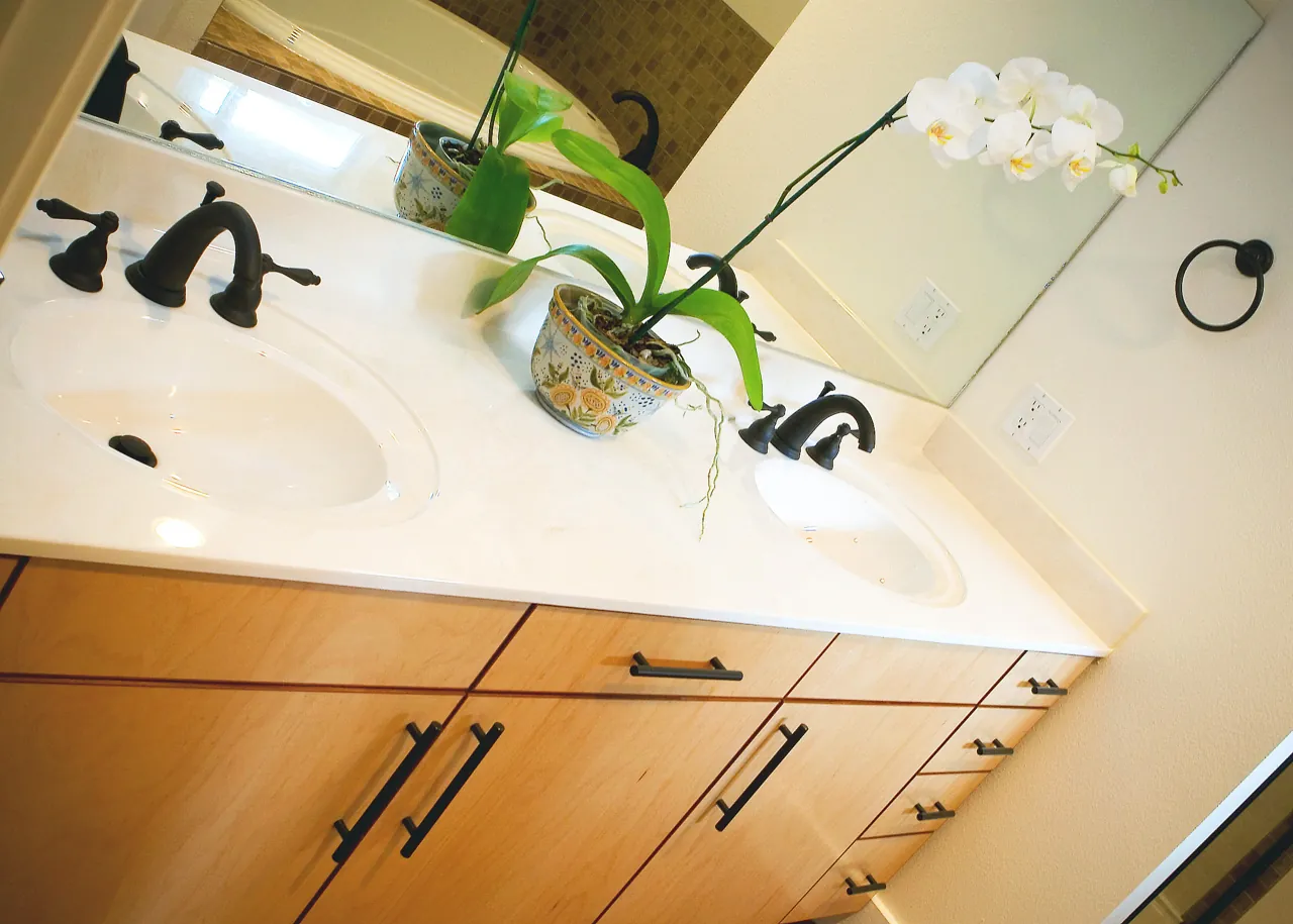 Double vanity with flat-panel light wood drawers and a white double-bowl top