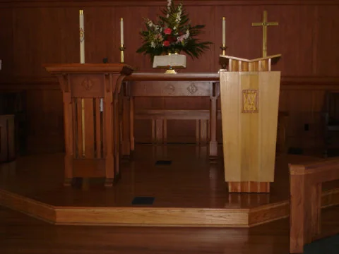Panelled chancel with an altar table, lectern and pulpit in warm cherry-tone wood