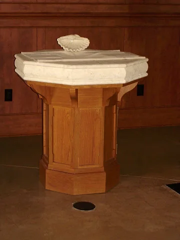 Octagonal wood base under a stone baptismal font