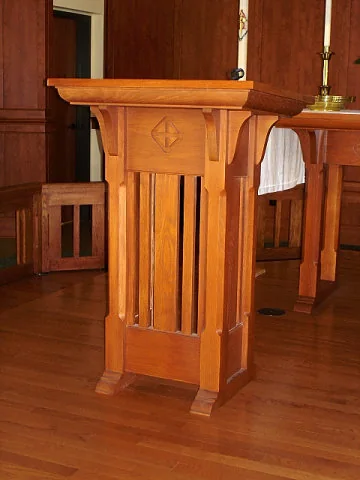 Wood lectern with slatted sides and a carved emblem